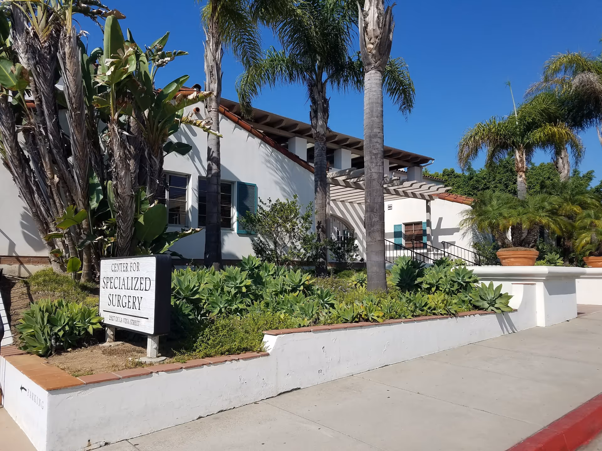 Exterior view of a white building with a Center for Specialized Surgery sign and palm landscaping.
