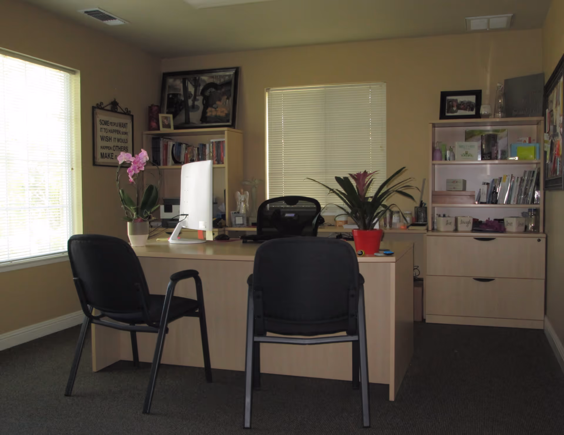 An office area with desks, chairs, plants, and storage shelves in a senior care facility.