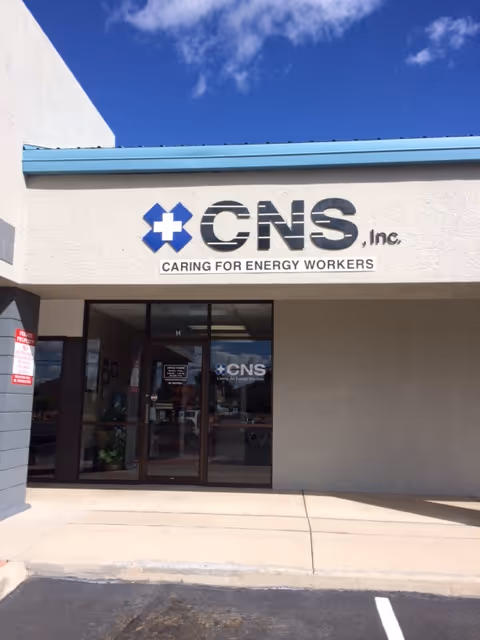 Exterior view of a building entrance with CNS, Inc. signage under a blue awning.