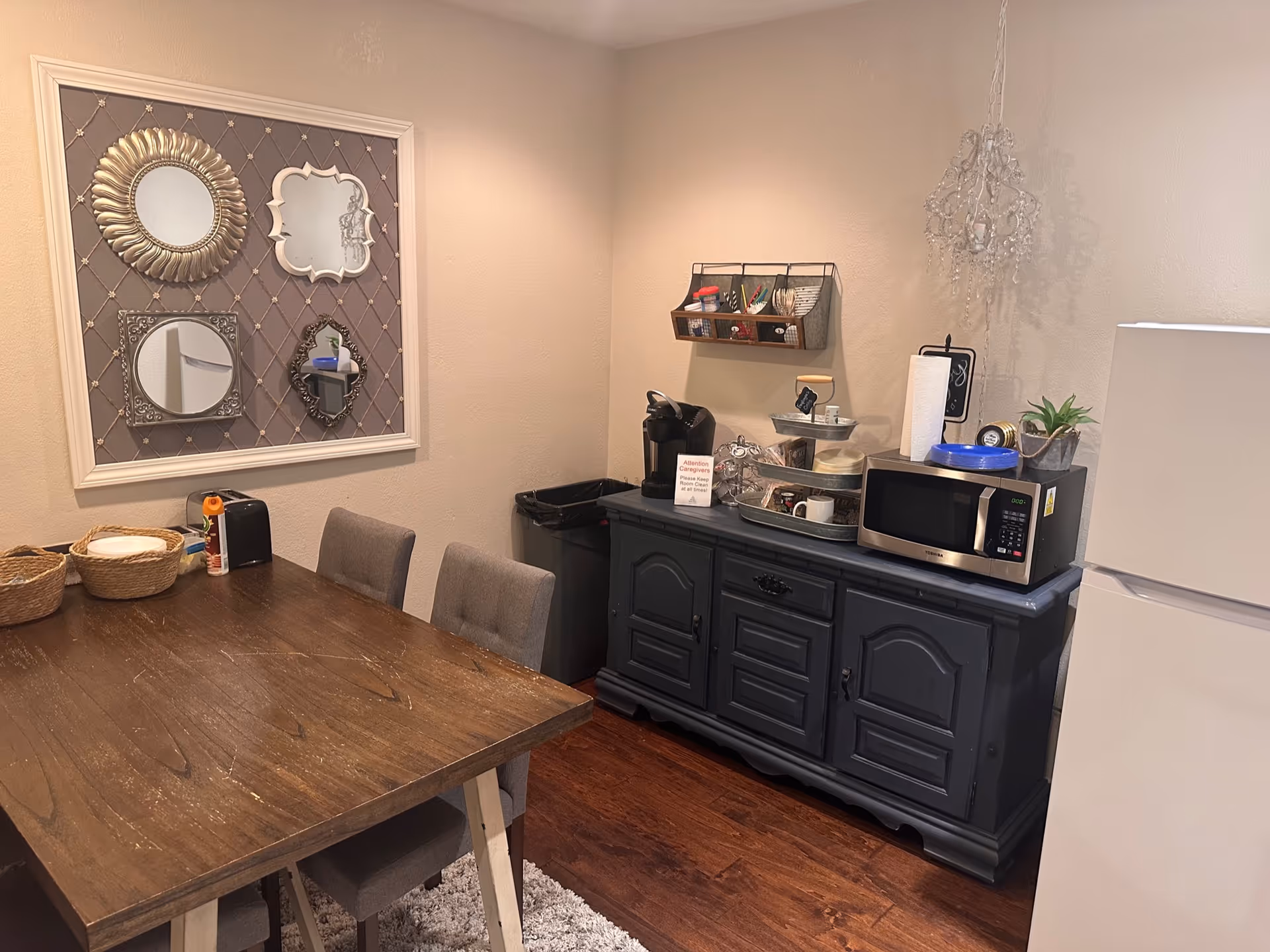 Dining area with wooden table, gray chairs, and a dark cabinet with microwave.