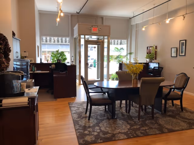 Interior view of a senior living common area with a round dining table and chairs.