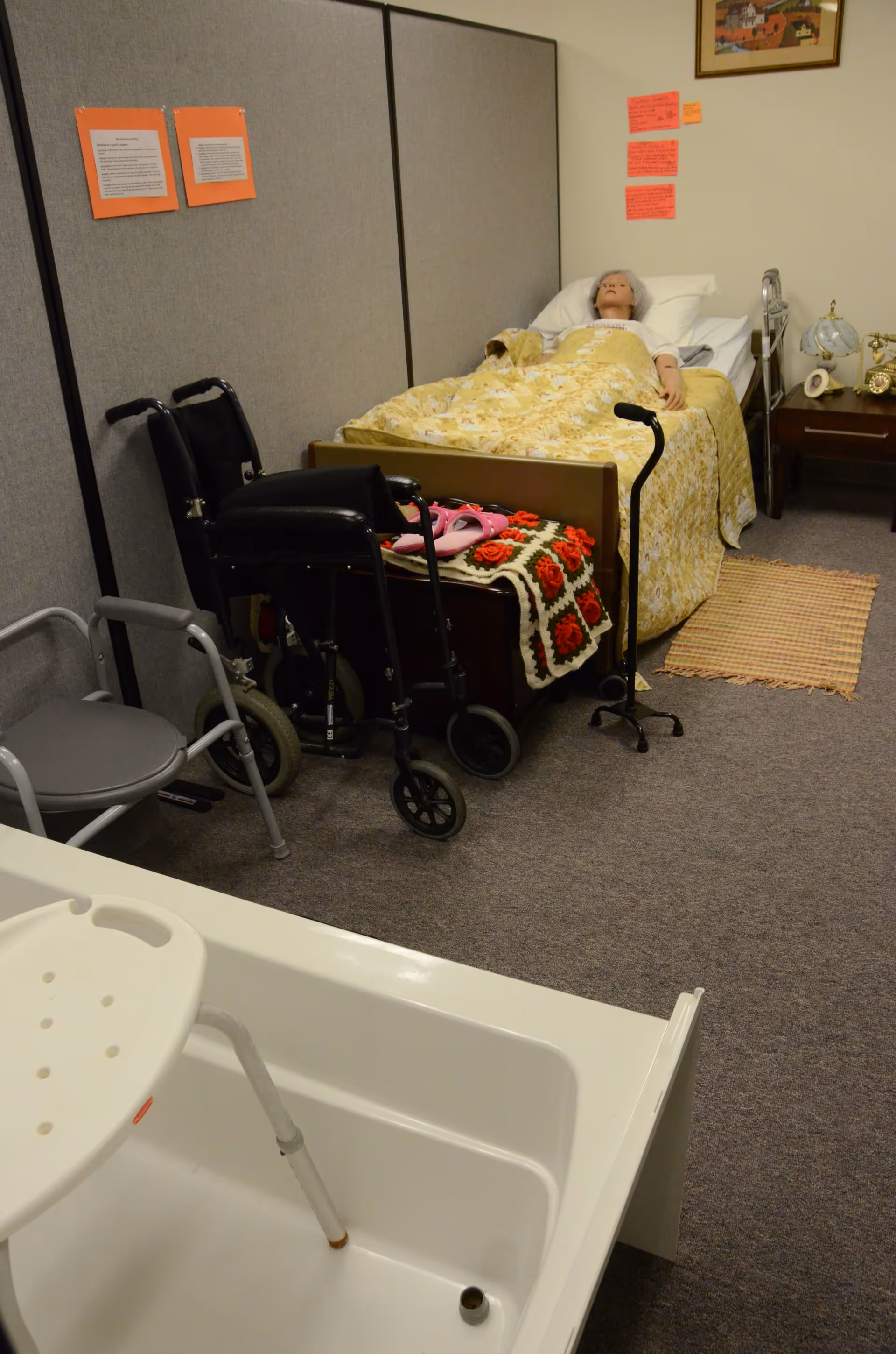Hospital-style room in a home care facility with bed, wheelchair, walker, and accessible bathtub.