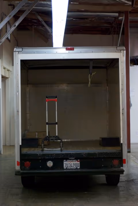 Open delivery truck in a loading bay with a hand truck inside.