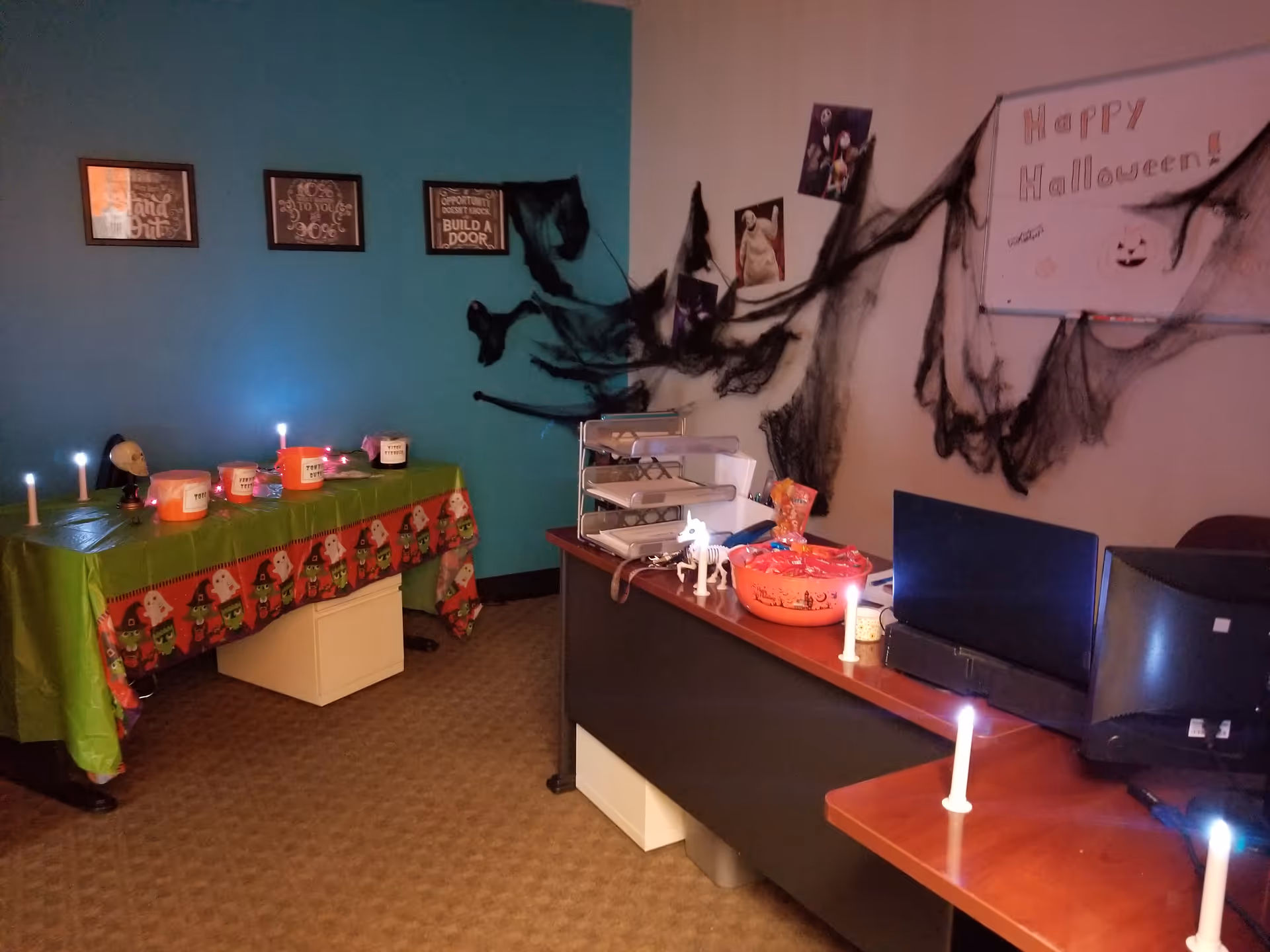 Interior reception area decorated for Halloween with cobwebs, candles, and a computer desk.