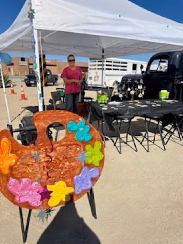 Outdoor event setup under a white tent, with a person and colorful decorations.