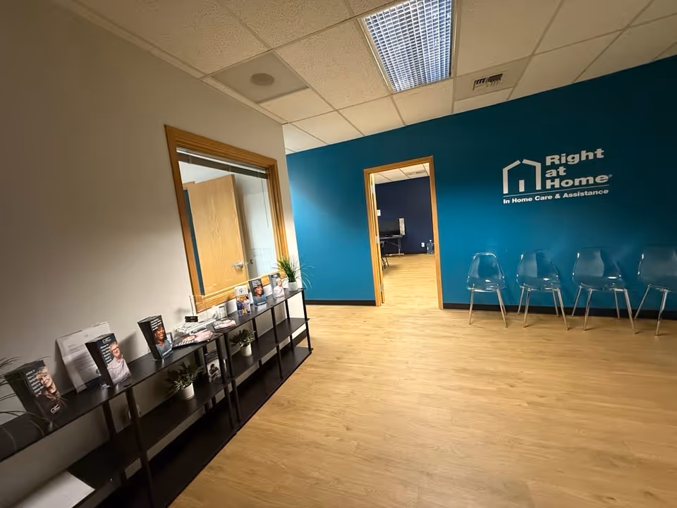 Reception area inside Right at Home with teal wall, brochure shelf, and row of chairs.