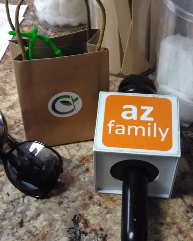Close-up on a countertop with a brown bag, sunglasses, and orange 'az family' block.