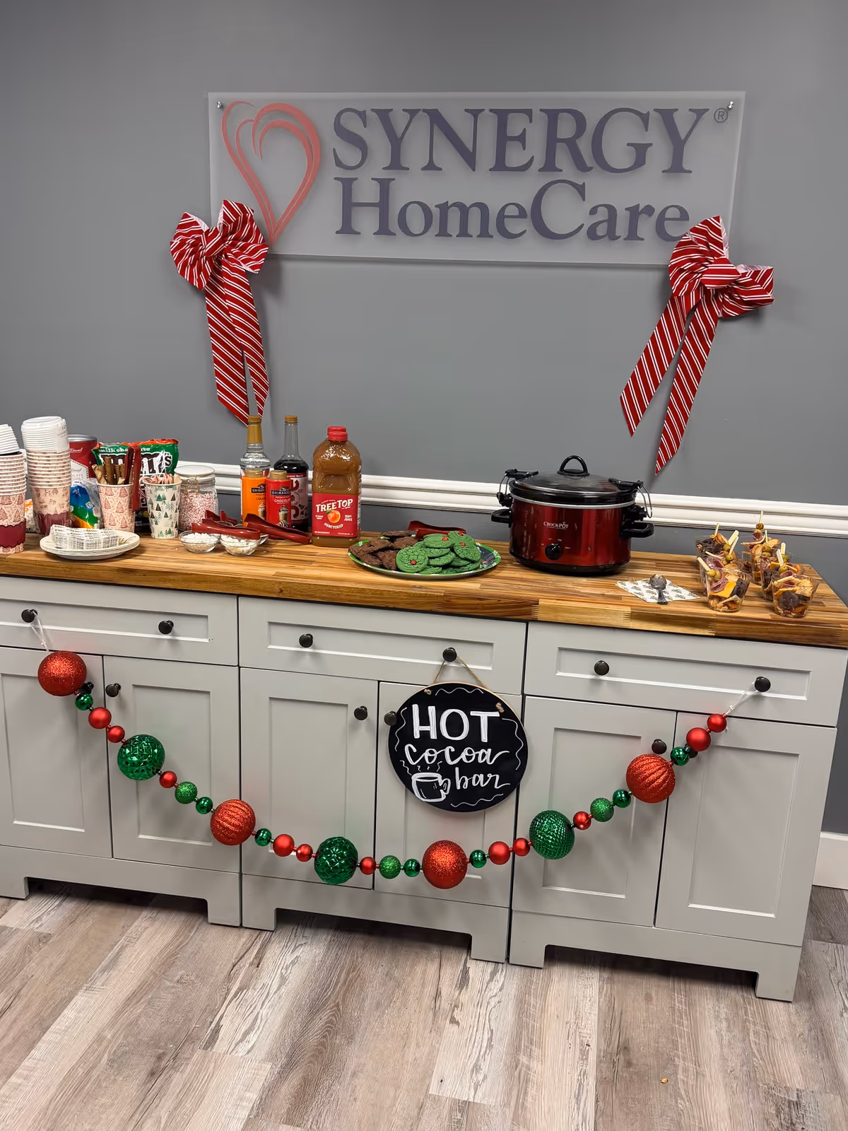 Synergy HomeCare sign above a holiday cocoa bar on a kitchen counter.