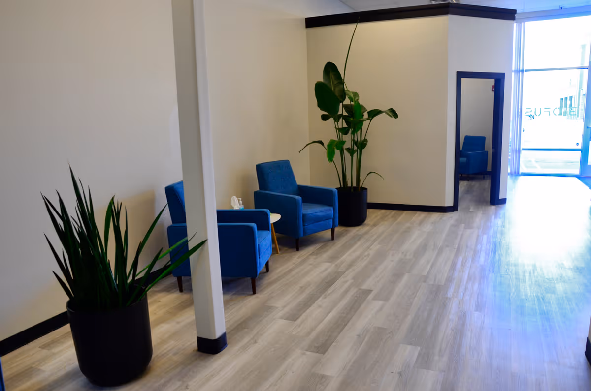 A modern facility lobby with blue chairs, potted plants, and a glass entrance.