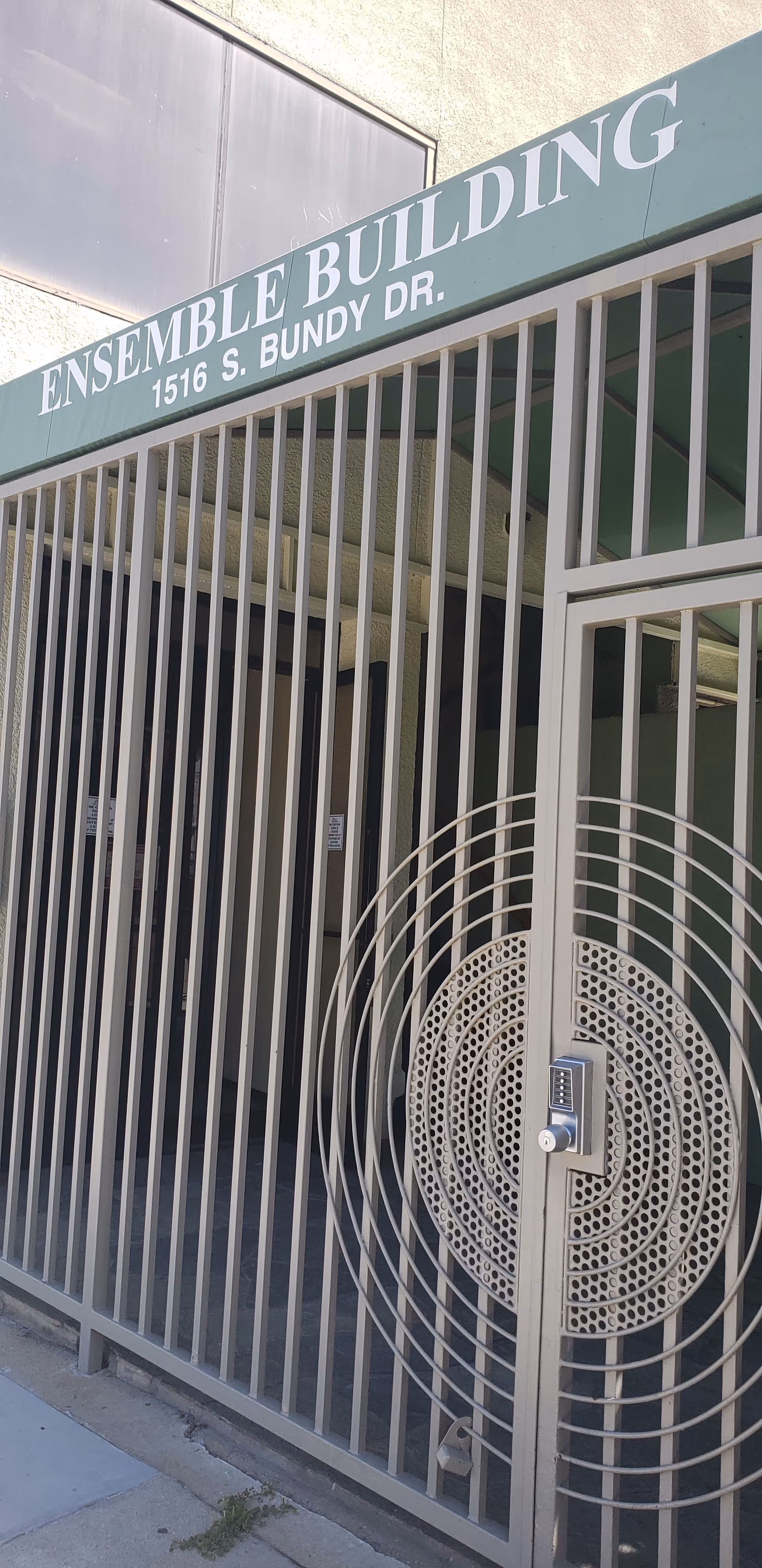 Exterior view of a gated building entrance with a circular security keypad