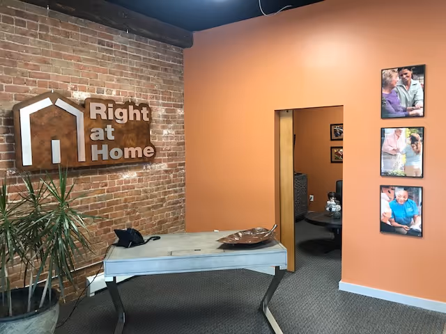 Lobby area with brick wall, Right at Home sign, orange accent wall, doorway, and photos.