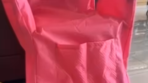 Pink chair covered in fabric sits in a tiled interior space.