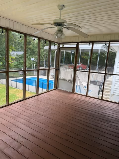 Screened porch with ceiling fan, wooden floor, and pool view outside.