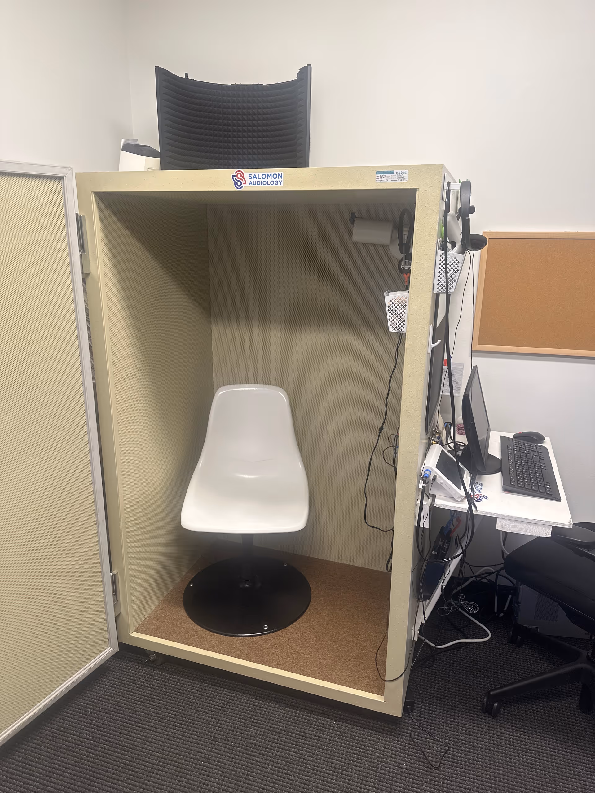 Salomon Audiology booth with a white chair, computer, and headset equipment.