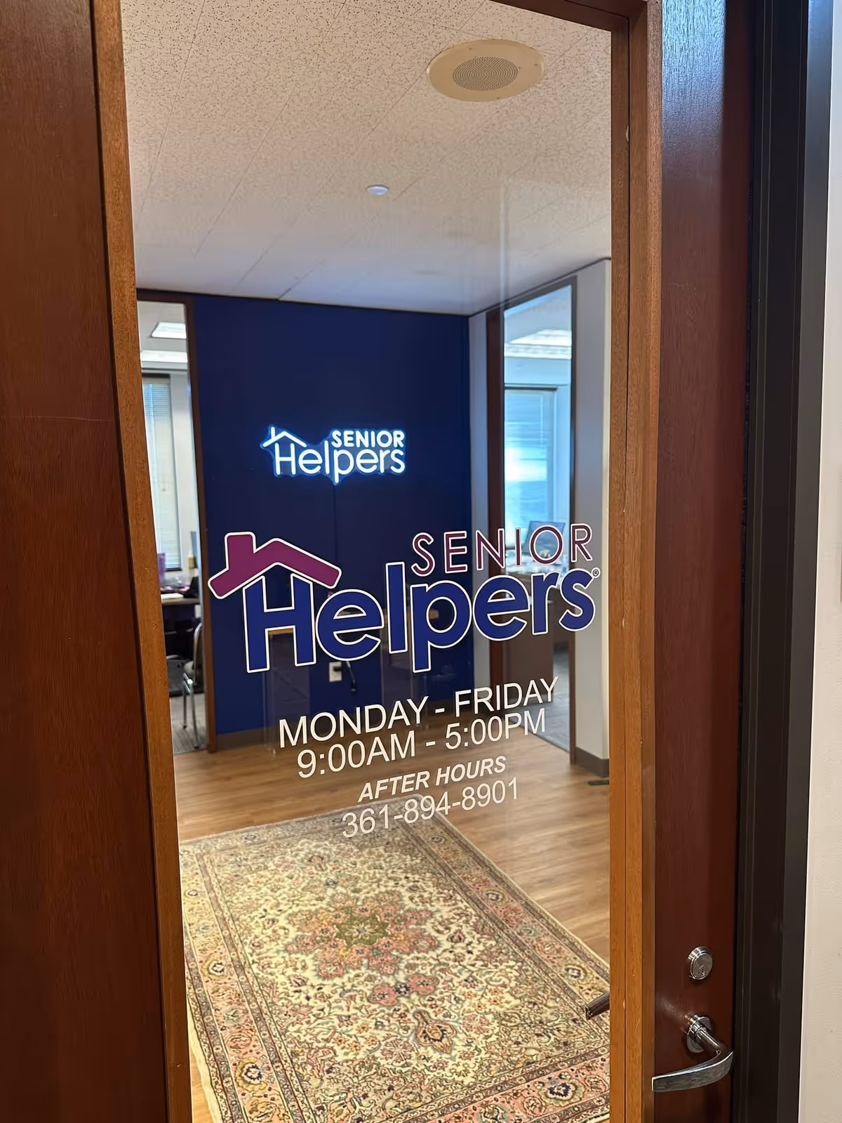 View through a doorway with Senior Helpers signage on a blue wall inside.