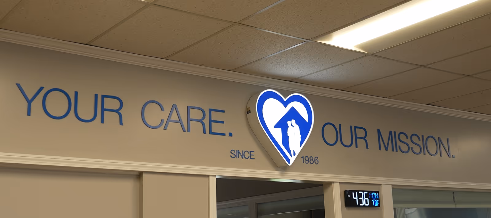 Interior hallway with a large blue motto sign and heart logo on the wall.