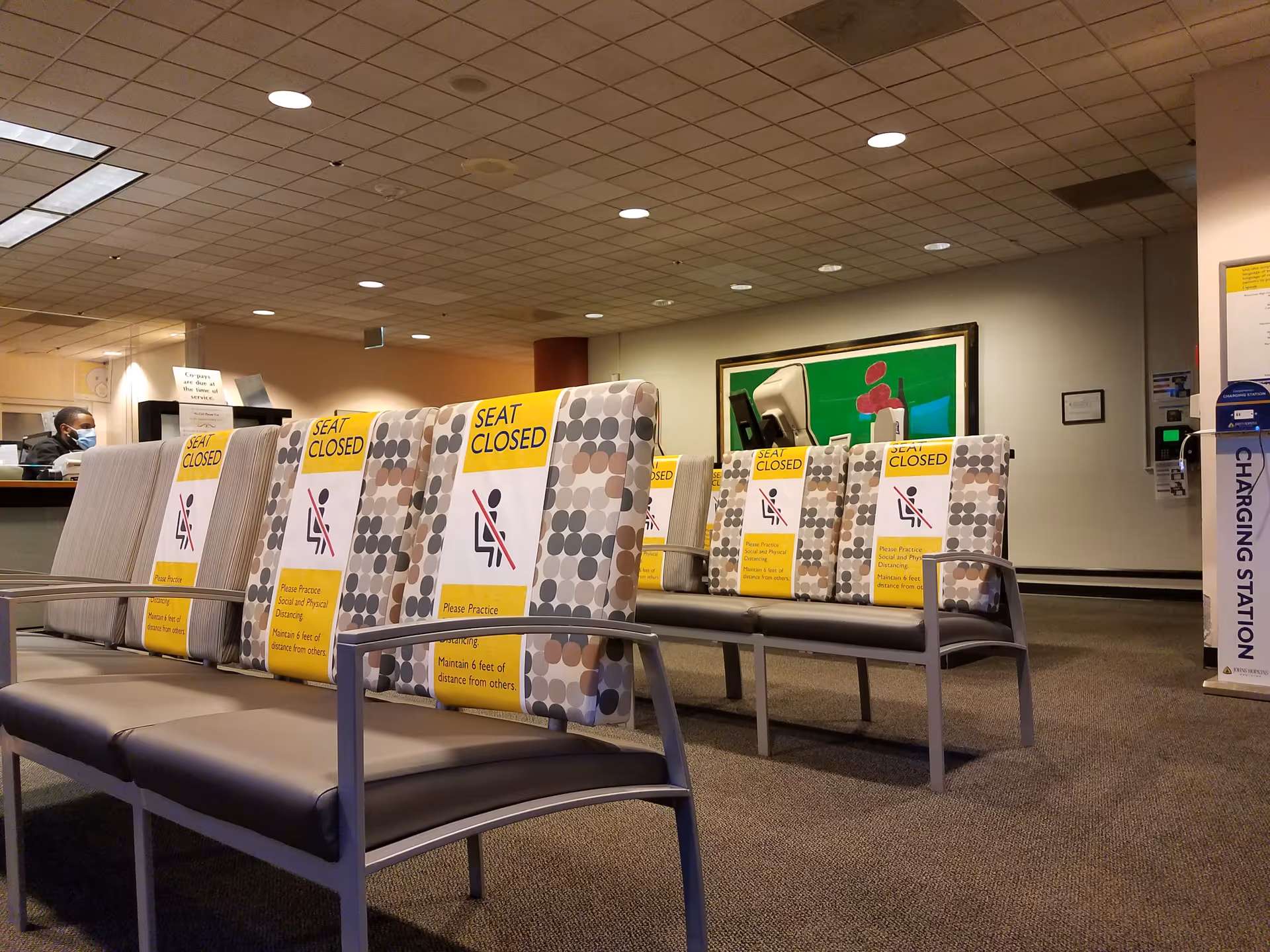 Johns Hopkins outpatient center waiting area with patterned chairs and 'Seat Closed' signs.
