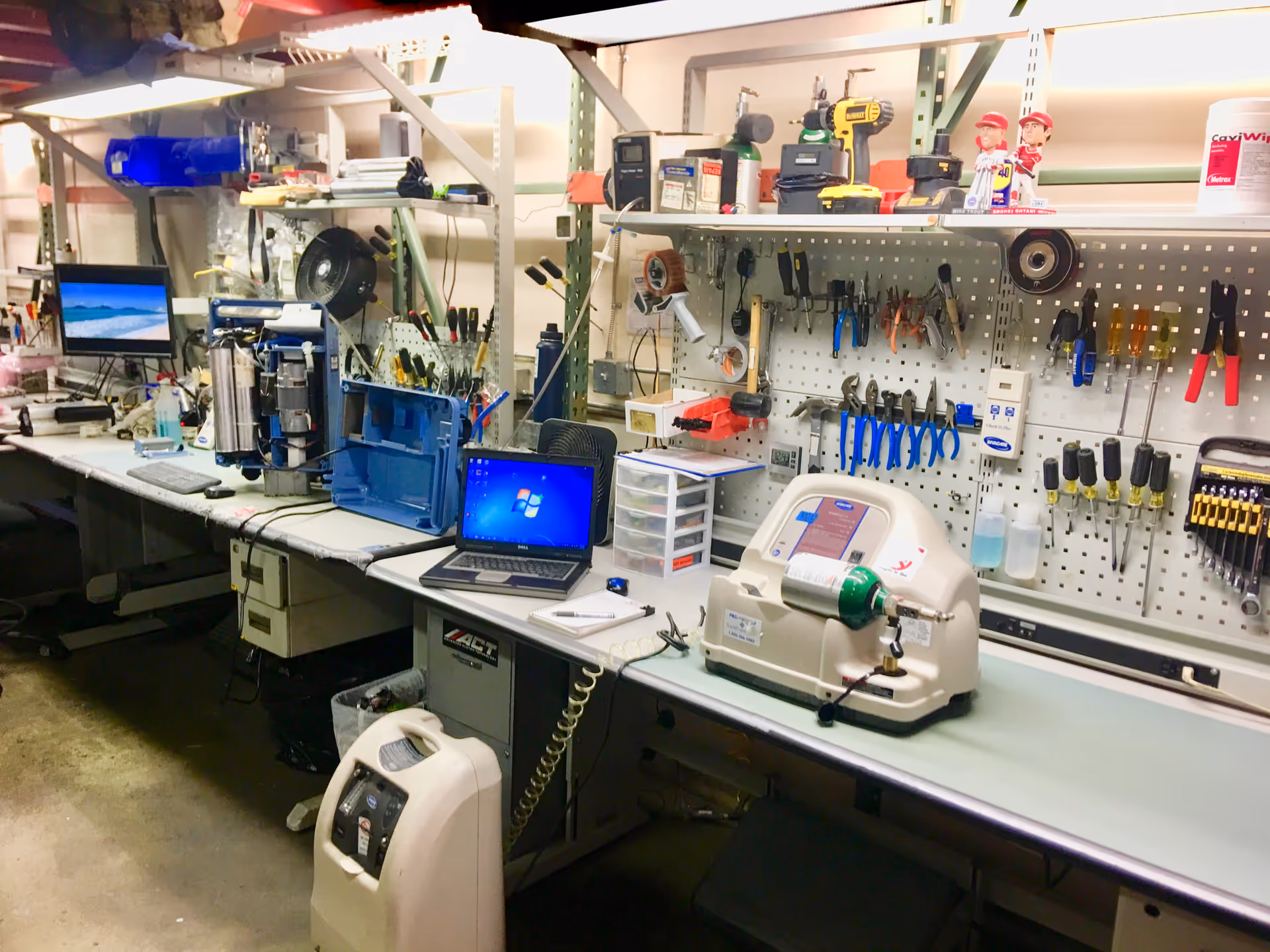 Cluttered repair bench with tools, a laptop, and equipment in a workshop.