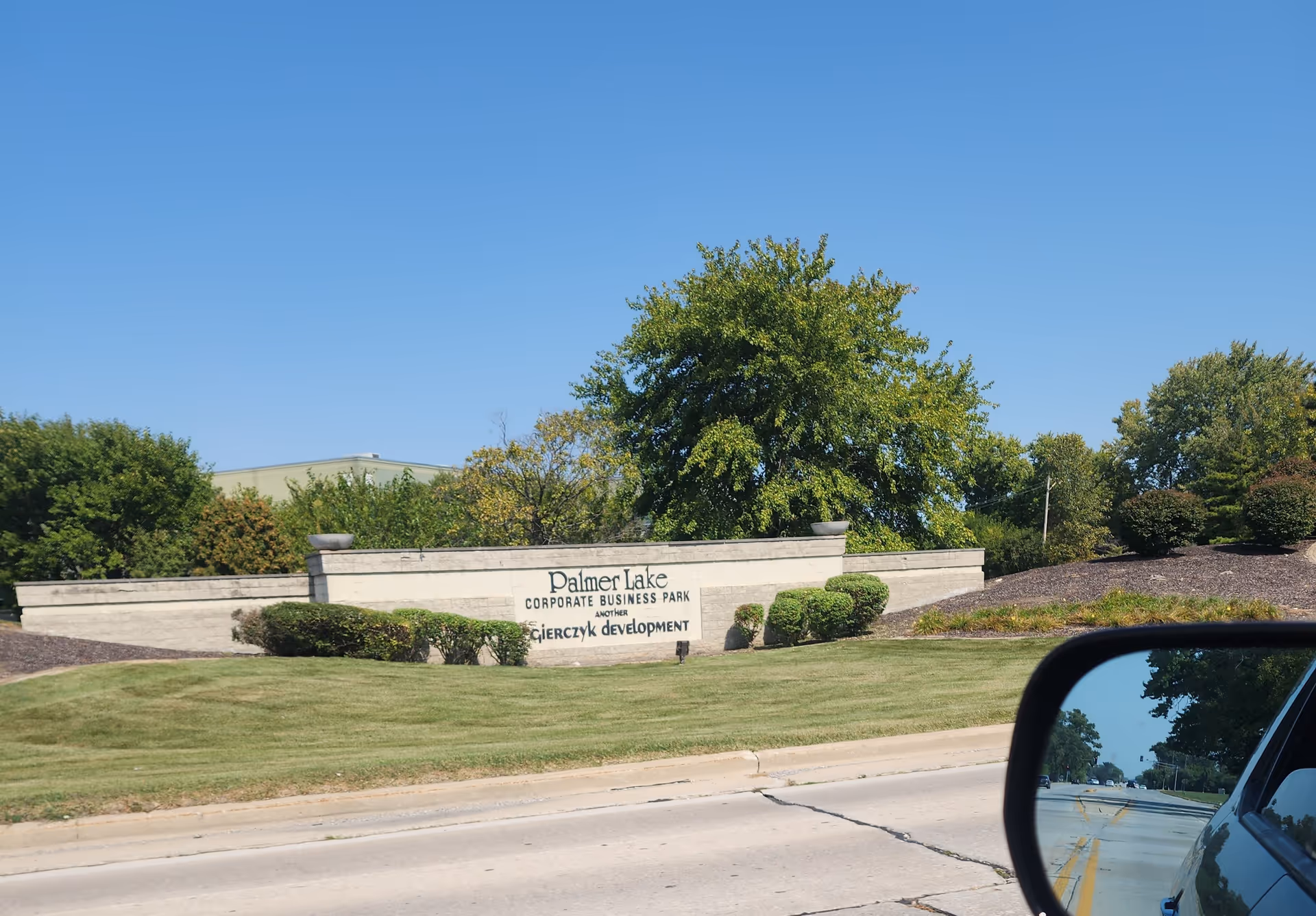 Exterior view of Palmer Lake Corporate Business Park sign with landscaping along a road