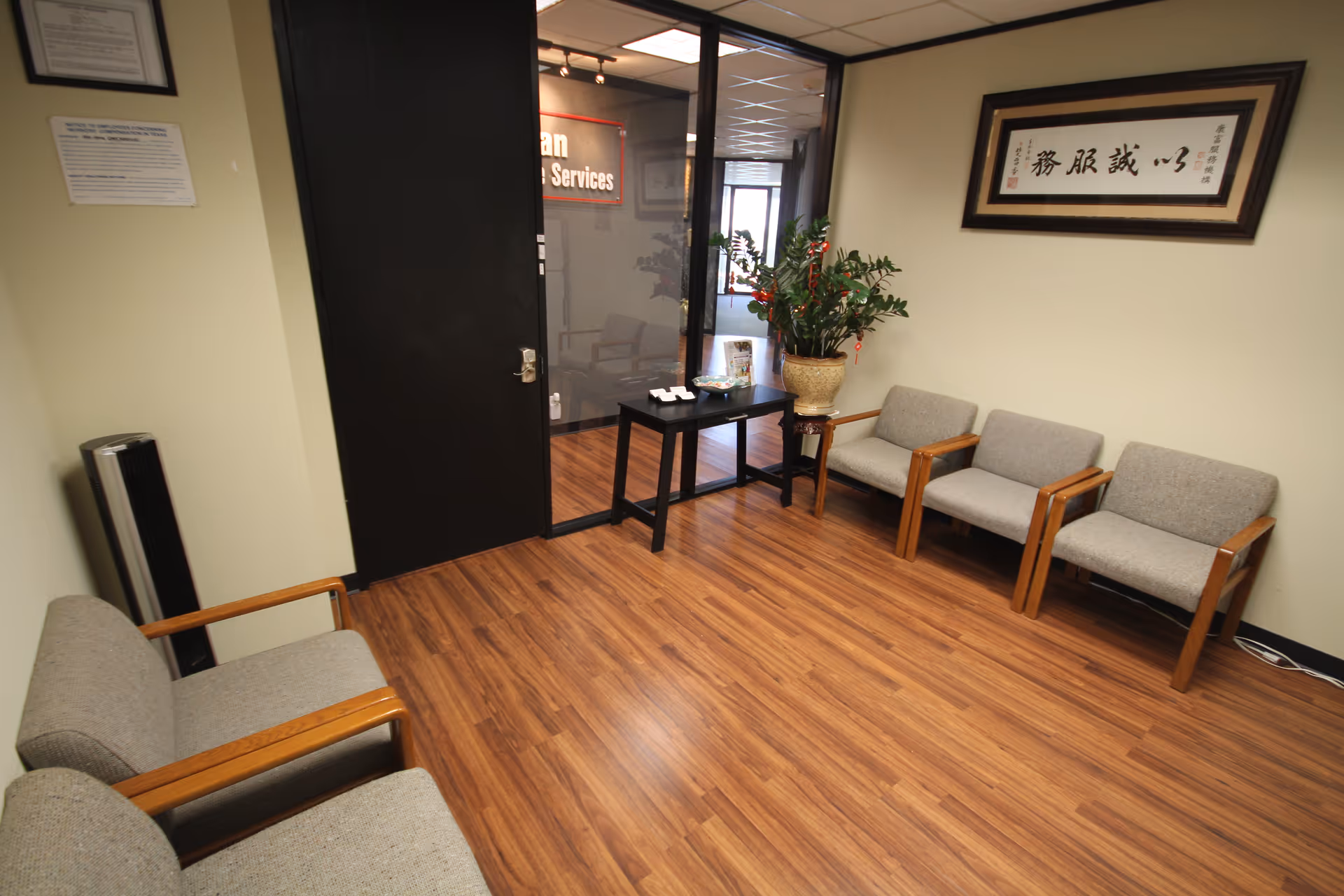 A waiting area inside a senior care facility with chairs, flooring, plants, and a glass door.