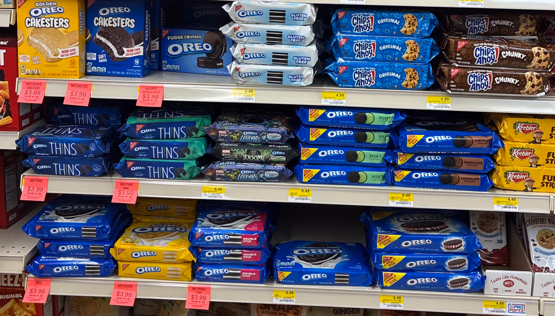 Grocery store shelves display Oreo cookies and Chips Ahoy snack packs.
