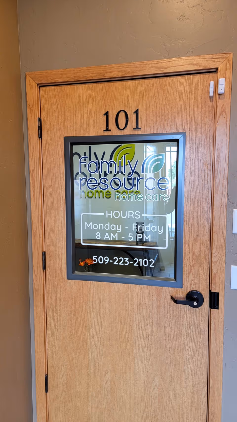 Wooden interior door labeled 101 with a window displaying Family Resource Home Care sign.