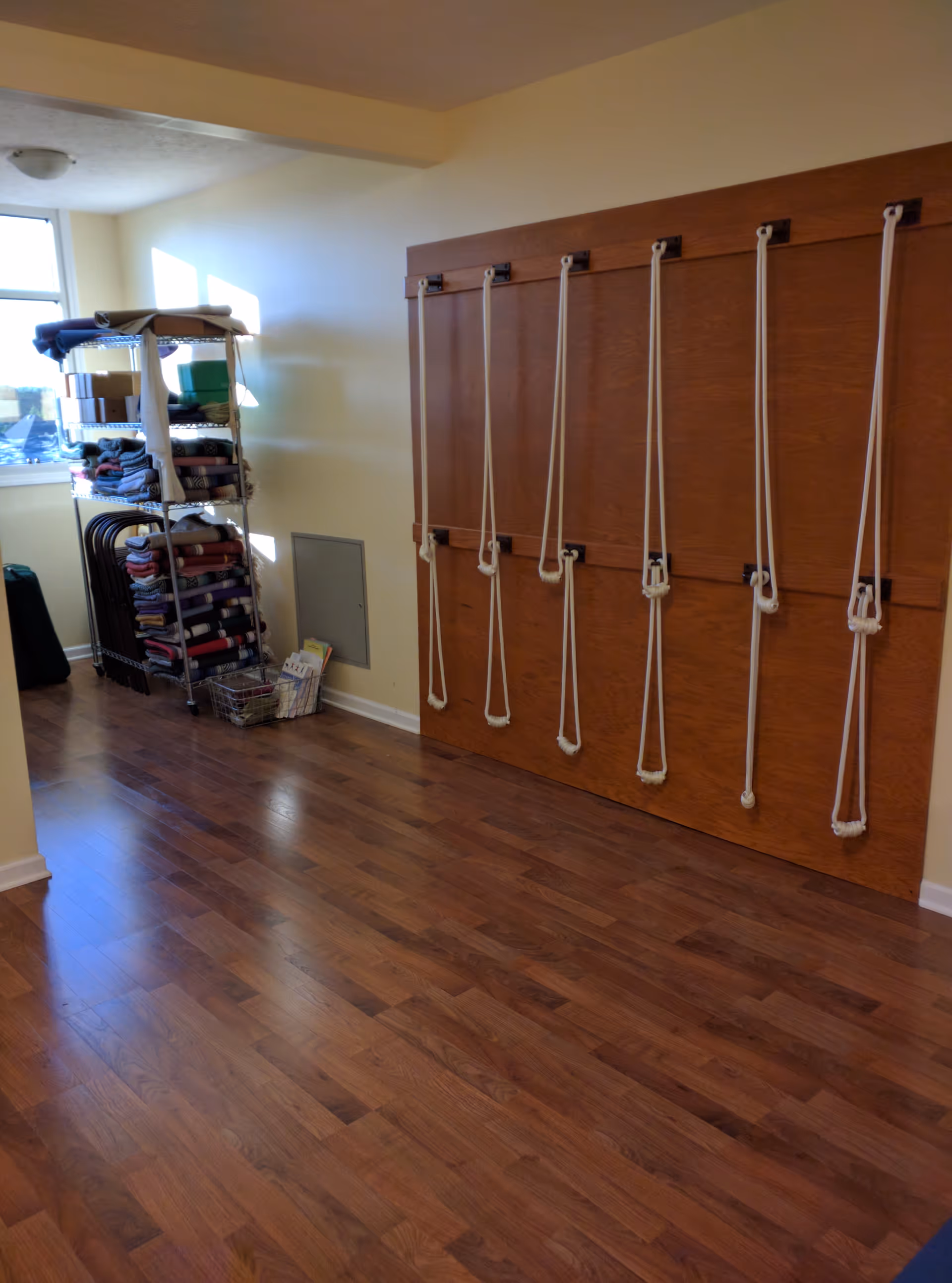 Interior rehab room with wall-mounted rope therapy setup and towel shelving.