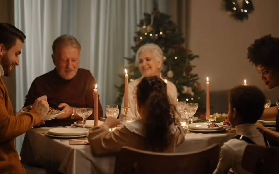 Group of residents dining at a candlelit holiday table indoors.