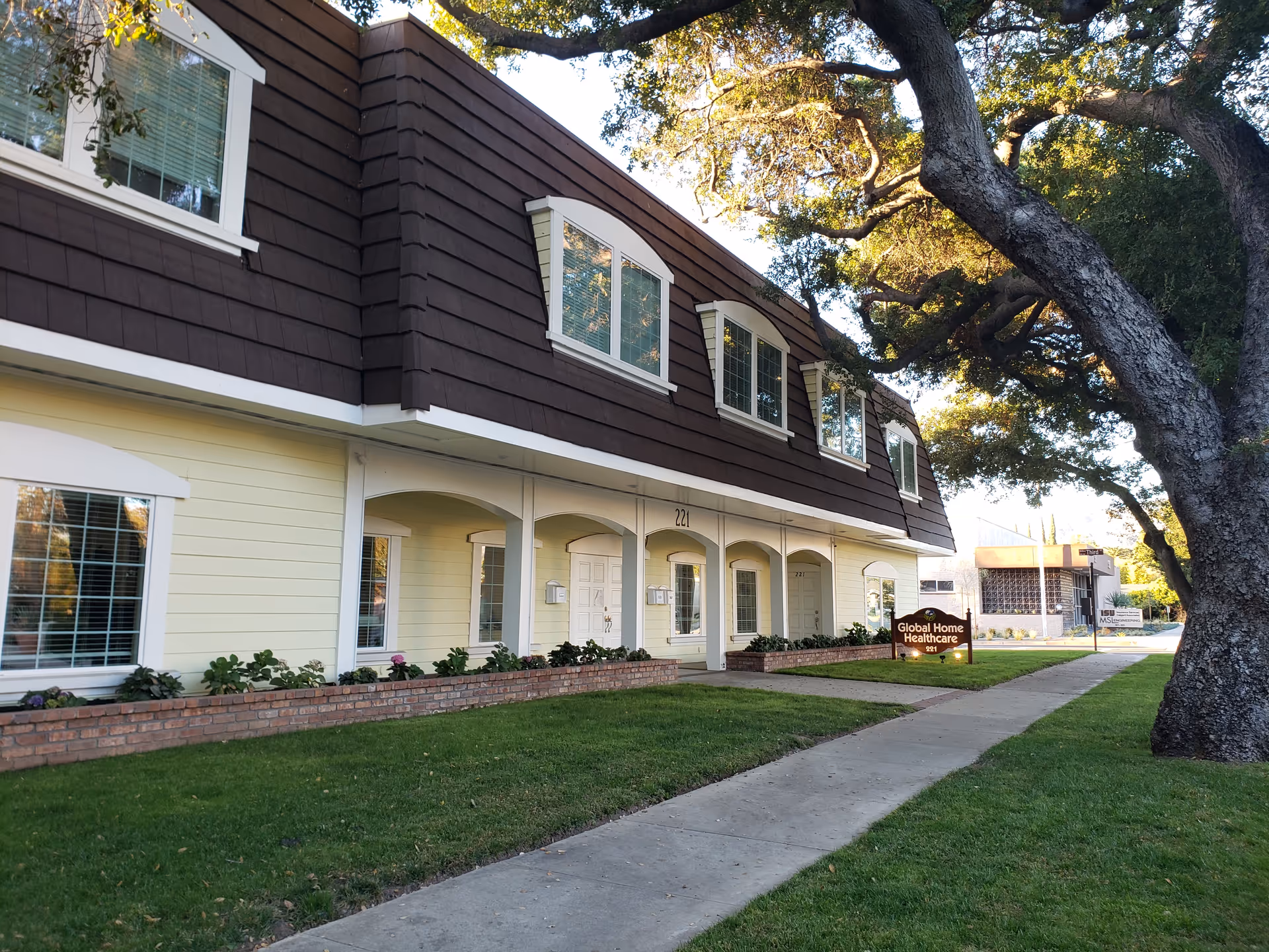 Exterior of a two-story facility with arched porches, dormer windows, and a green lawn.