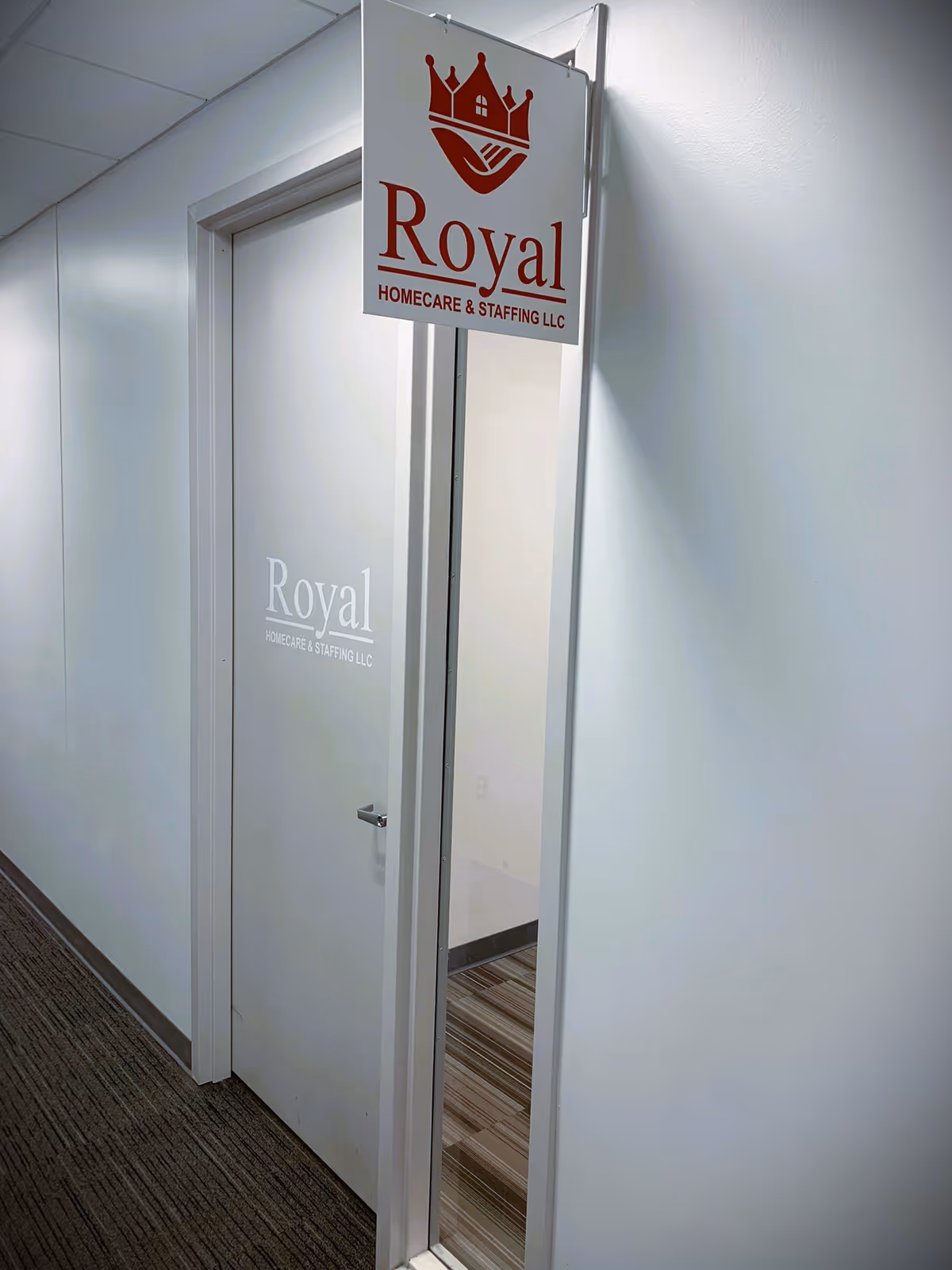 Indoor hallway with a hanging Royal Homecare sign above a frosted door