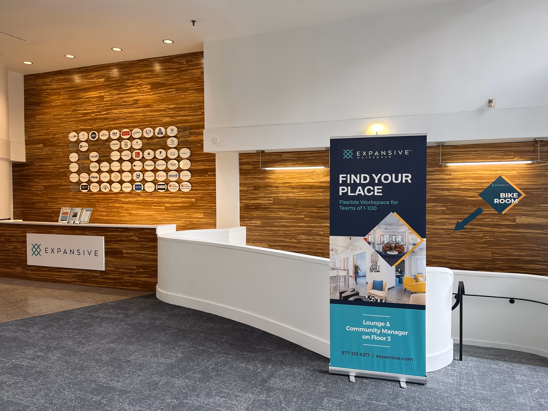 Modern facility lobby with wood panel wall, reception desk, and promotional banner.