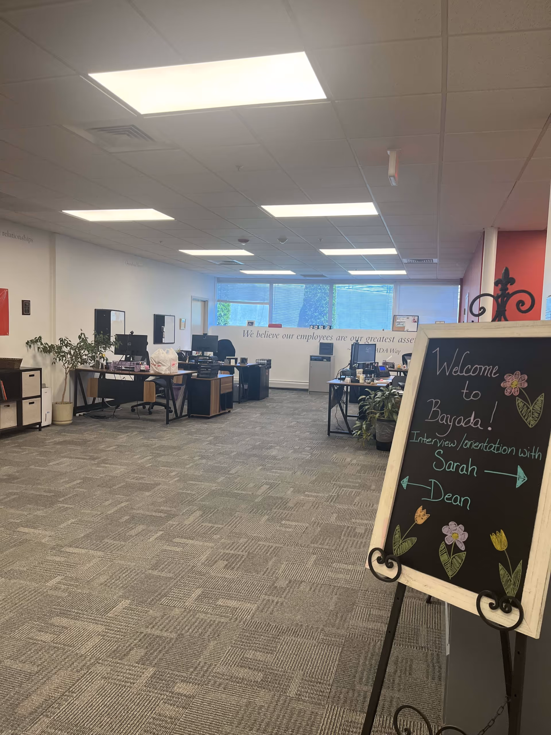 Interior office space with desks, computers, and a chalkboard welcome sign.