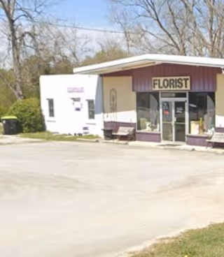 Exterior front of a small florist shop with purple trim and glass doors