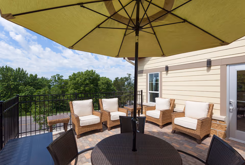 Lakeside Oasis outdoor terrace with wicker chairs, table, and large umbrella.