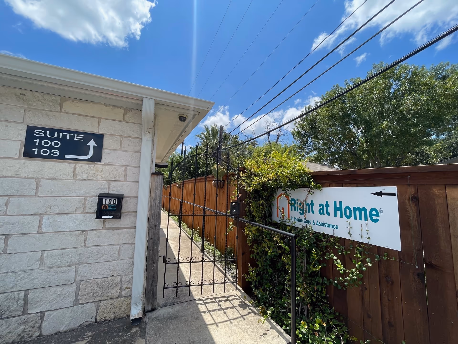 Exterior view of Right at Home facility entrance with gate and directional sign.