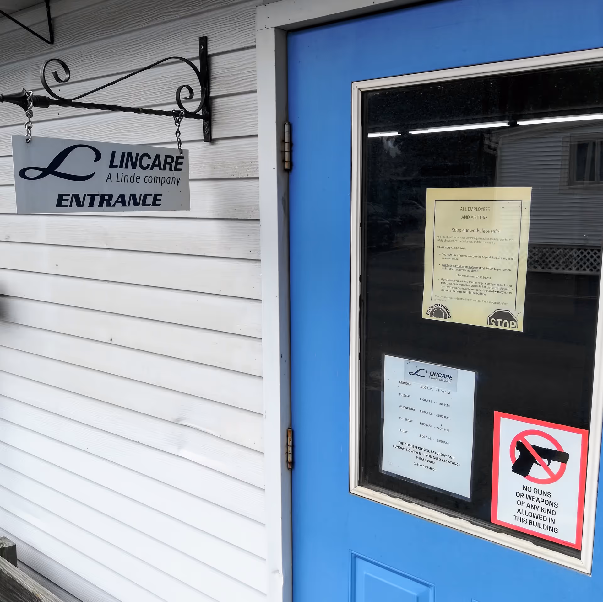Exterior view of a blue door entrance with a LINCARE sign on white siding.