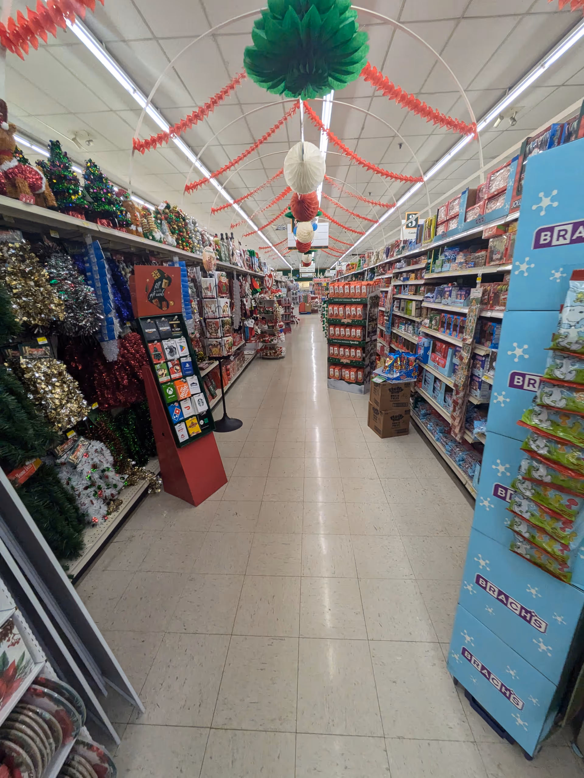 A narrow store aisle packed with holiday decorations and products on shelves.