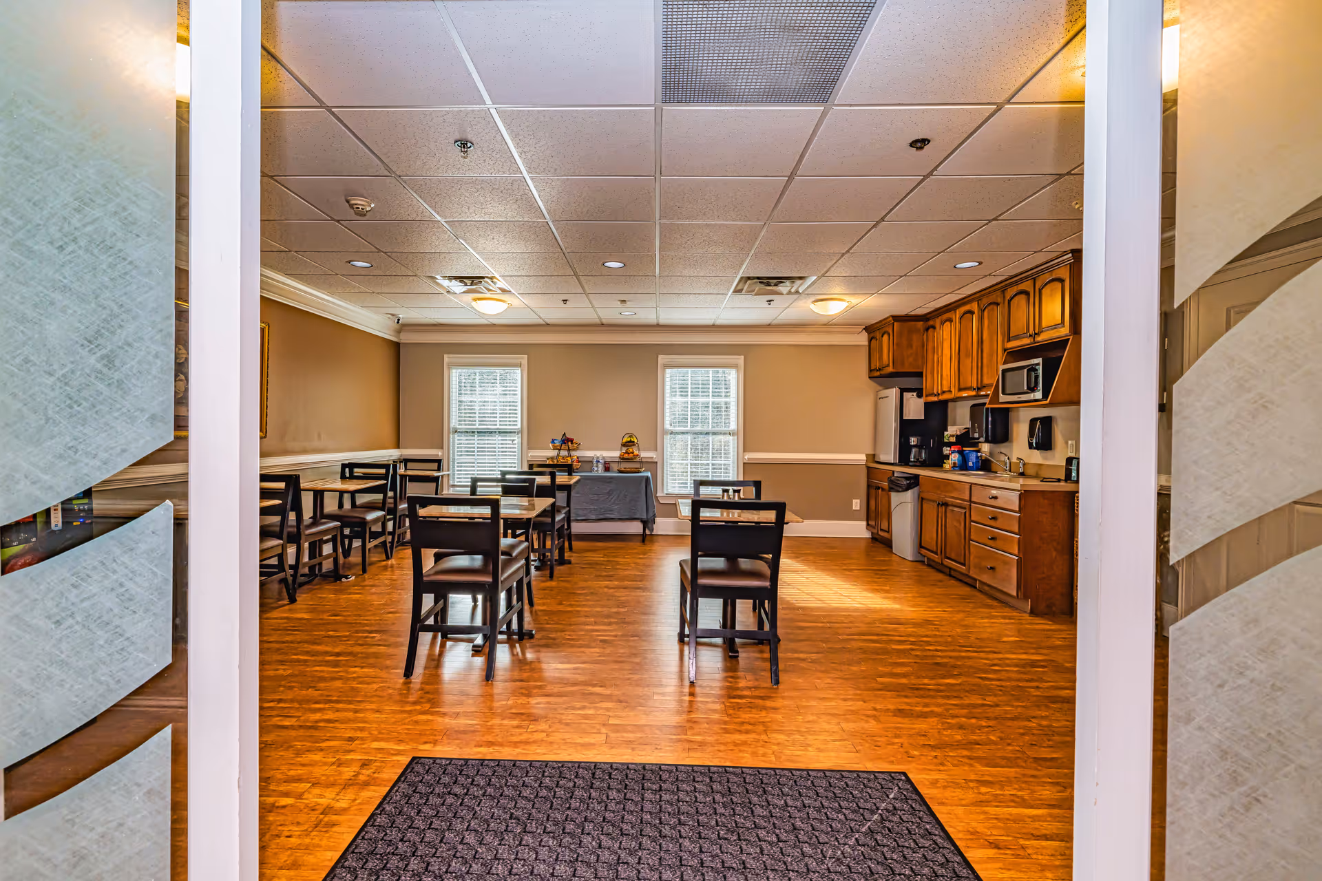 Interior dining area with tables, chairs, and a kitchenette along the right.