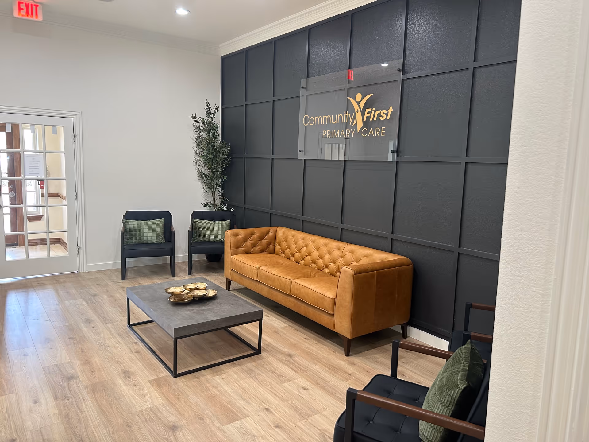 Modern waiting area with dark paneled wall, leather sofa, and assorted chairs.