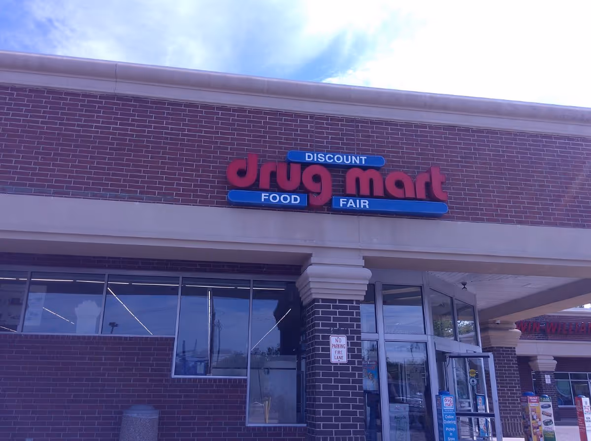 Front exterior of Discount Drug Mart storefront with brick façade and large blue sign.