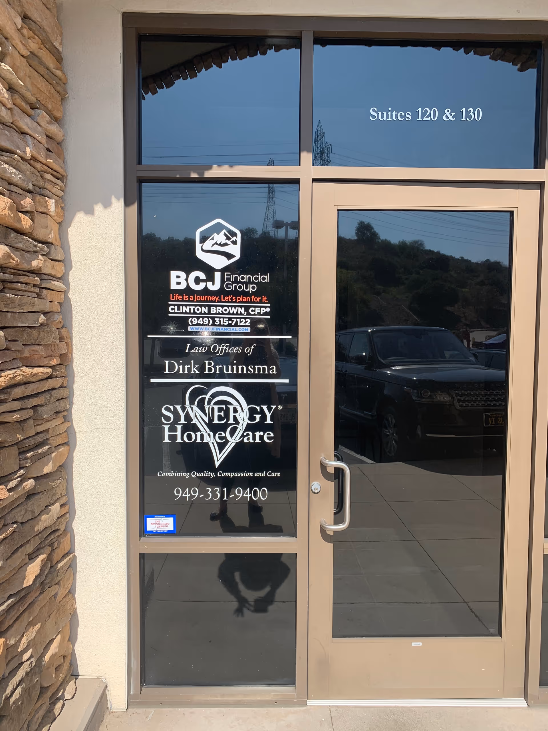 Glass entrance door with Synergy HomeCare logo on a stone-front building