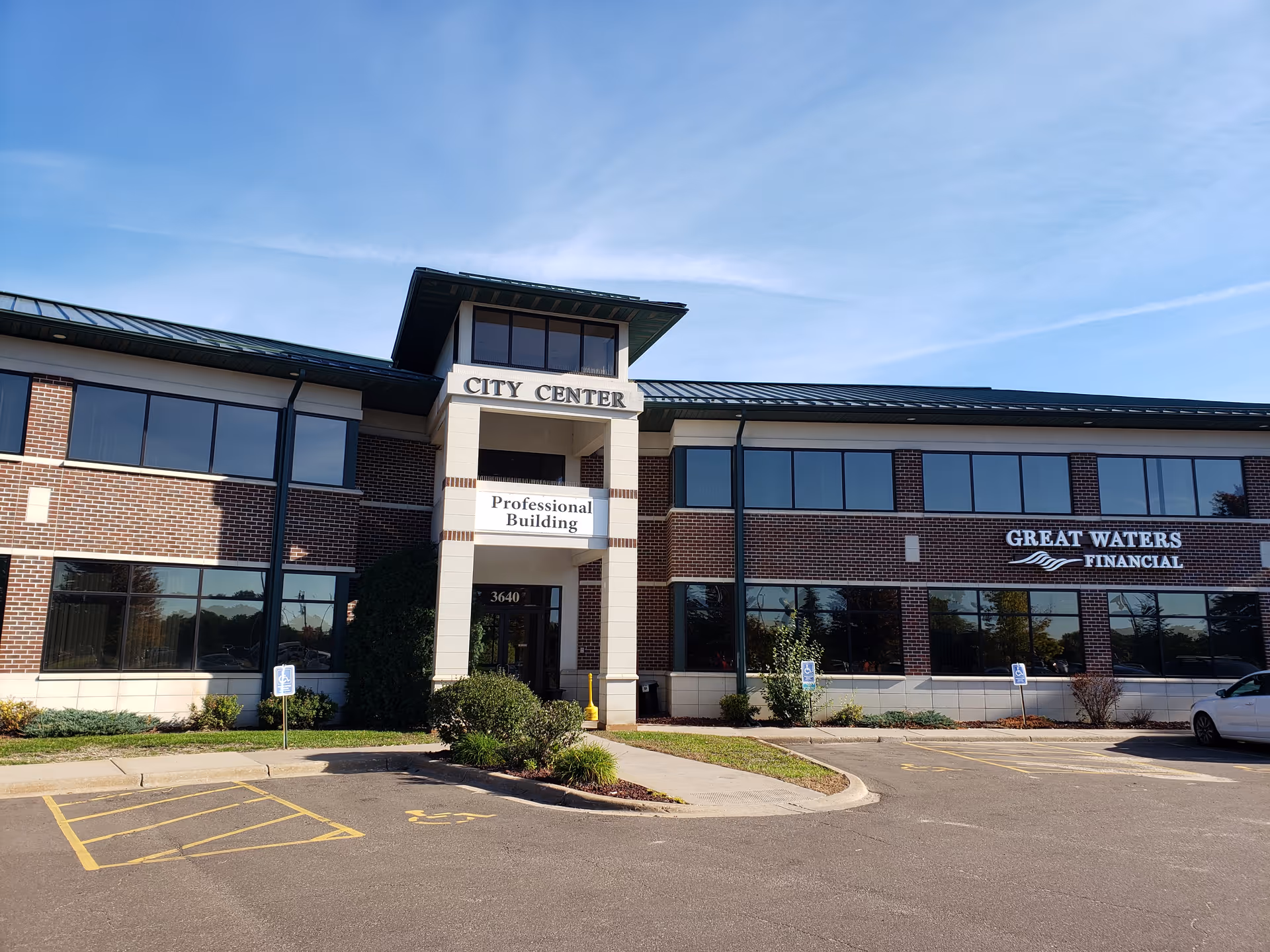 Exterior view of a brick professional building with large windows and parking lot.