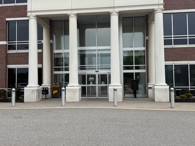 Front entrance of a brick facility with tall white columns and glass doors.