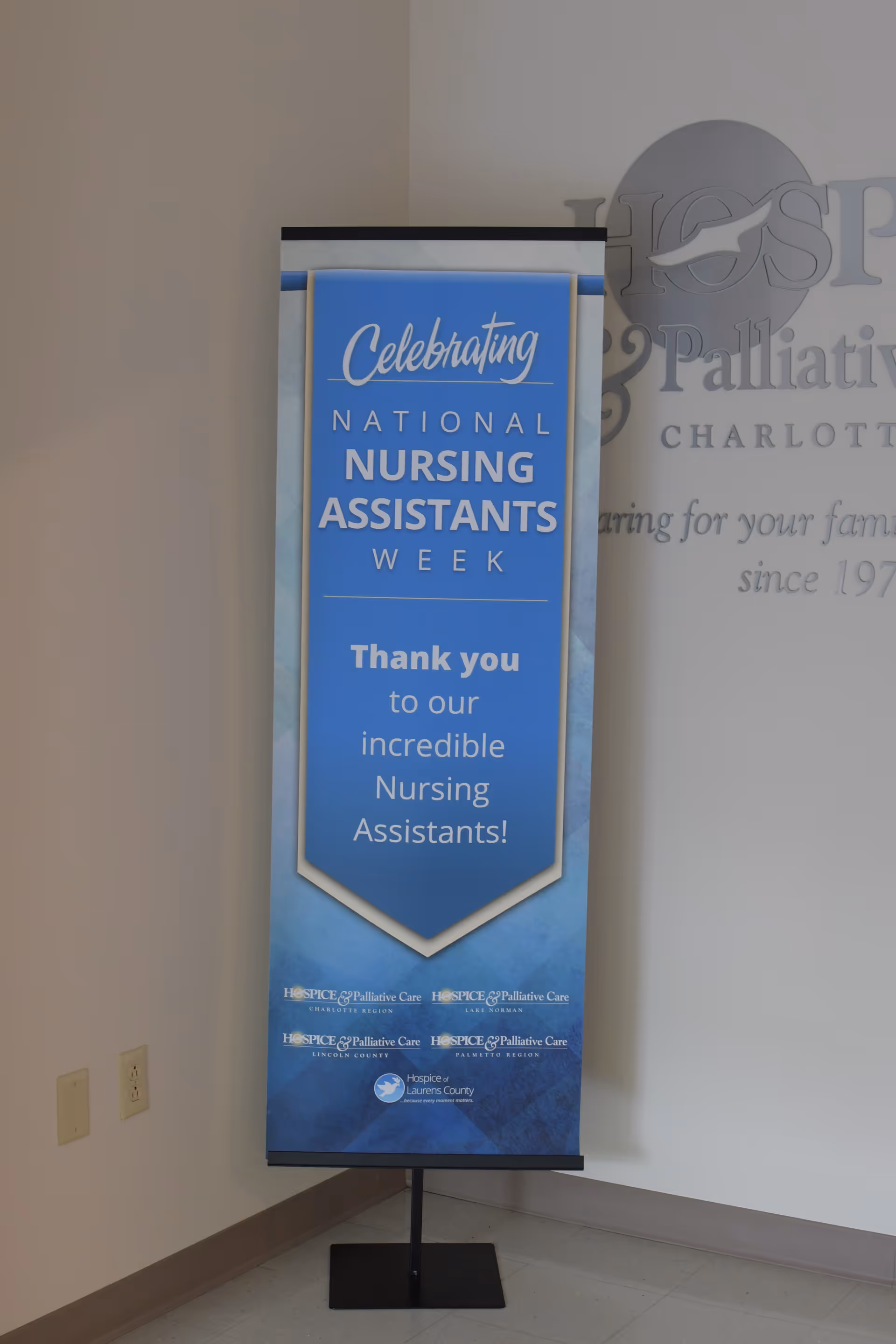 Blue signage banner in an interior hallway celebrating National Nursing Assistants Week for VIA Health Partners.