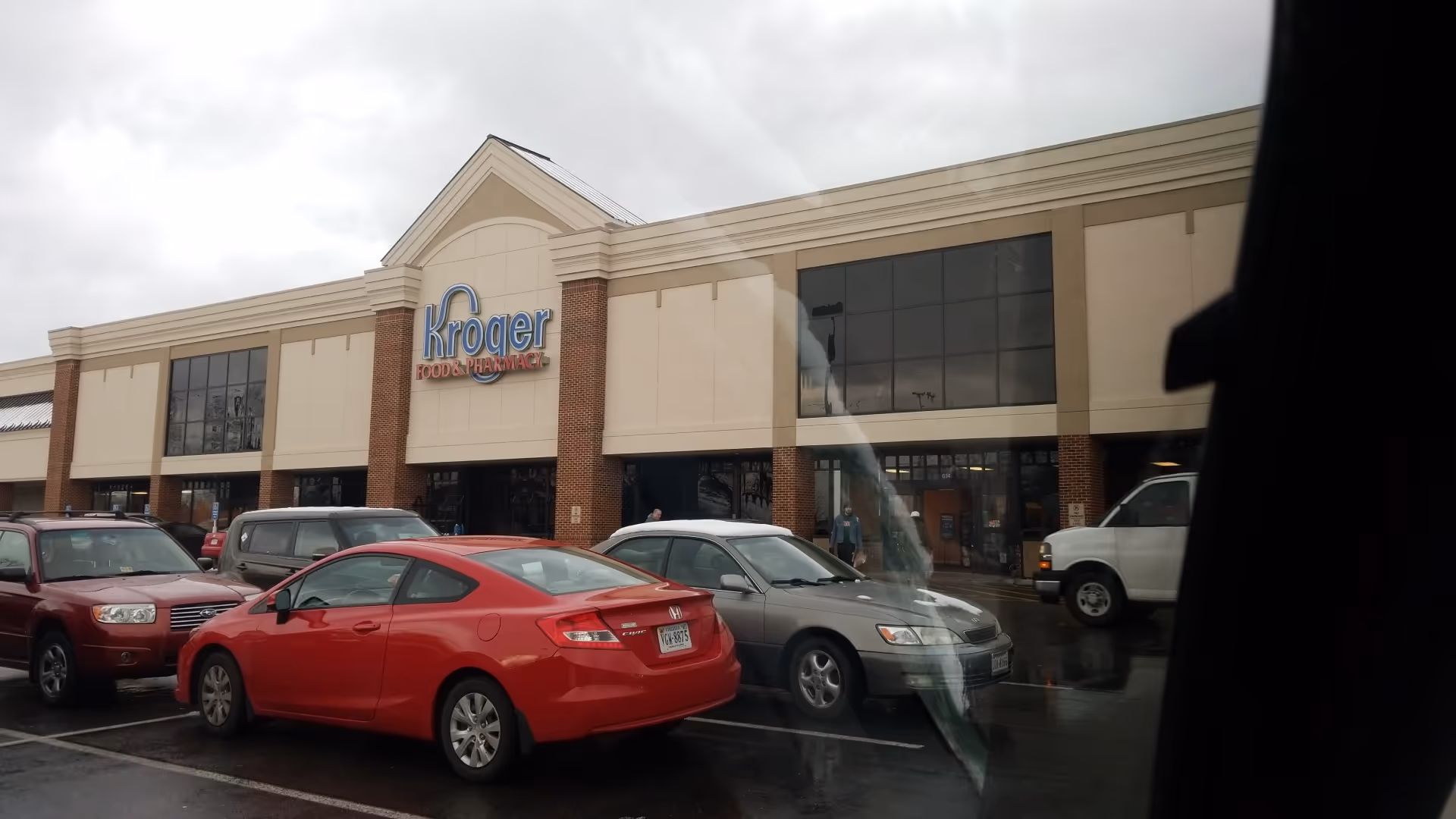 Exterior view of a Kroger Pharmacy storefront with parked cars.