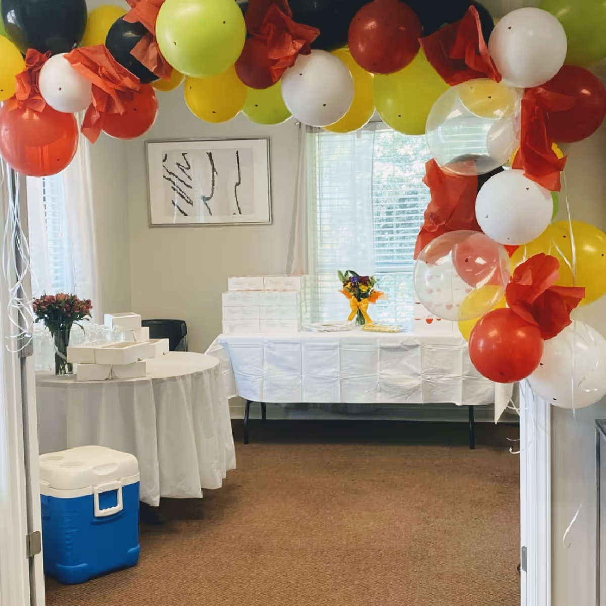 Interior room decorated with colorful balloons and tables for a celebration.