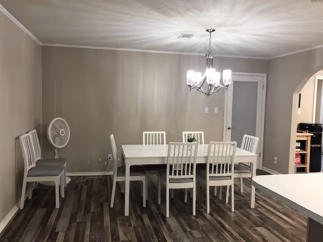 White dining table and chairs under a chandelier in beige dining room