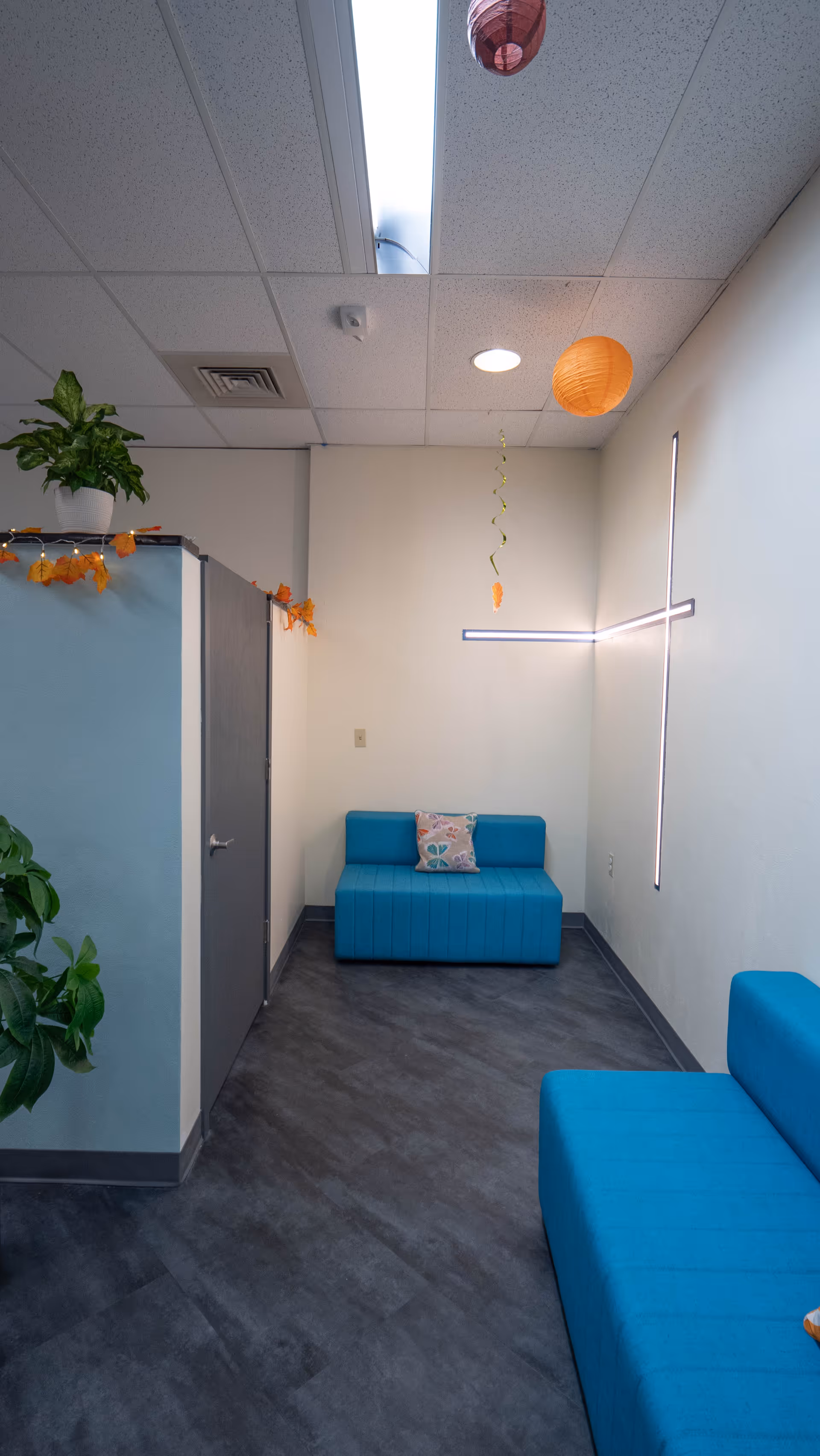 Plain hallway in a facility with blue seating and hanging lanterns.