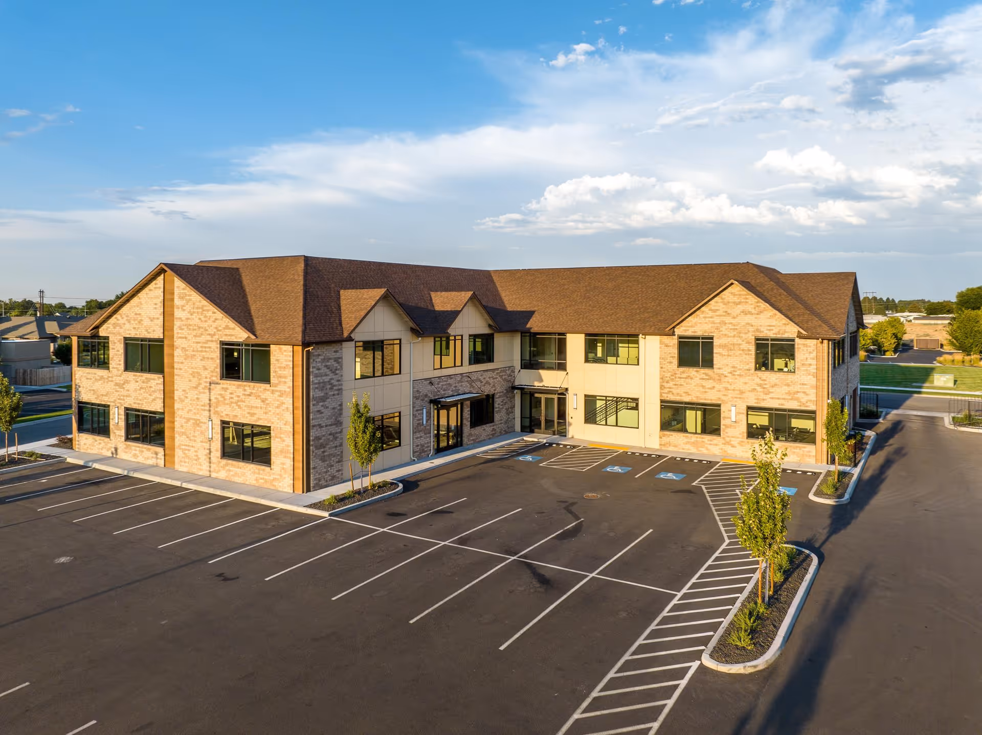 Aerial view of a two-story brick senior living facility with a parking lot.