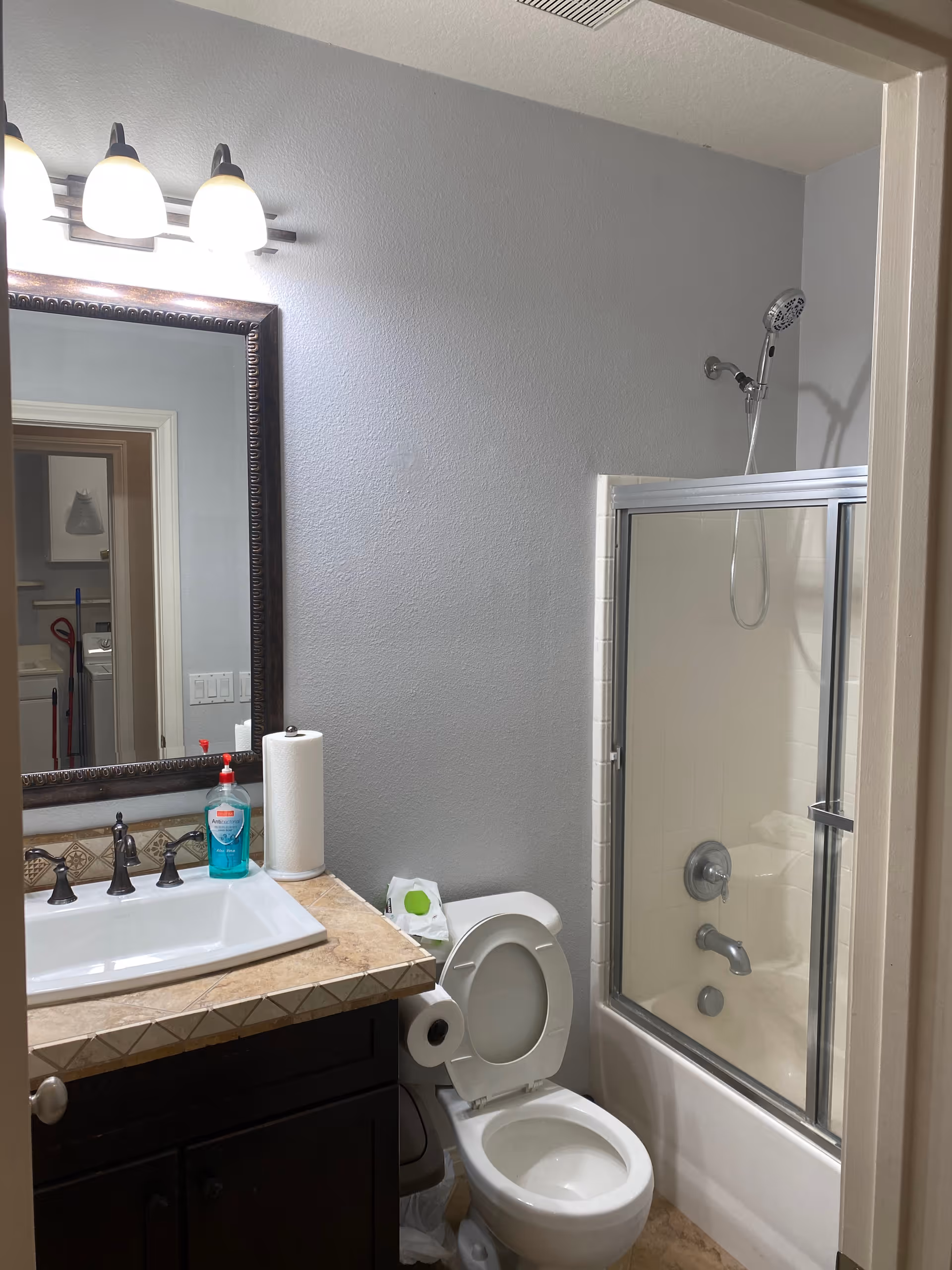 Bathroom with sink, toilet, and glass-door shower in a senior living facility.